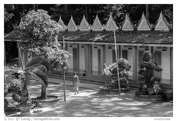 Monk walking past huts, Hang Pagoda. Tra Vinh, Vietnam (black and white)