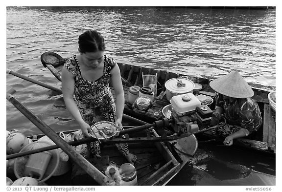Woman gets bowl of noodles from floating market. Can Tho, Vietnam (black and white)