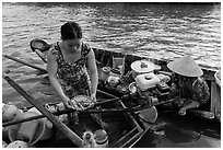 Woman gets bowl of noodles from floating market. Can Tho, Vietnam ( black and white)
