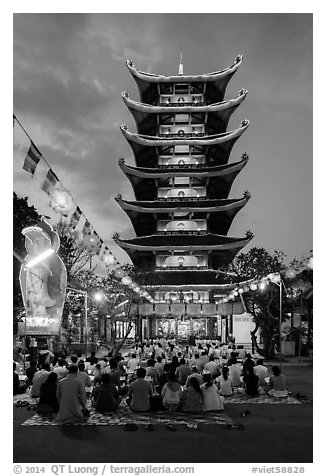 Worshippers and seven story  Quoc Tu pagoda at dusk. Ho Chi Minh City, Vietnam (black and white)