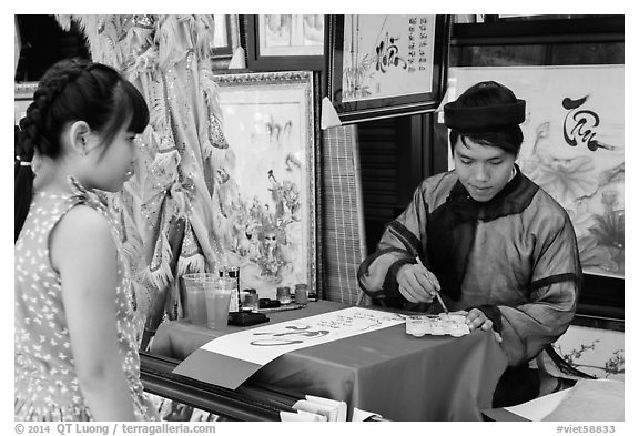 Caligrapher draws Tet greetings as woman looks on. Ho Chi Minh City, Vietnam (black and white)