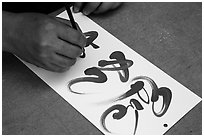 Hands drawing Tet (Lunar New Year) greetings in Chinese characters. Ho Chi Minh City, Vietnam ( black and white)