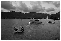 Men in coracle boat paddling in Con Son harbor. Con Dao Islands, Vietnam ( black and white)