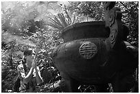 Tourist praying at an urn with incense near the entrance of Phong Nha Cave. Vietnam (black and white)