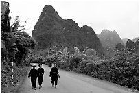 Villagers in traditional garb walking down the road with limestone peaks in the background, Ma Phuoc Pass area. Northeast Vietnam (black and white)