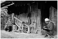 Elderly woman sewing  on her doorstep as kids look up. Northeast Vietnam ( black and white)