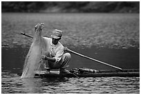 Fisherman retrieves net from a dugout boat. Northeast Vietnam (black and white)