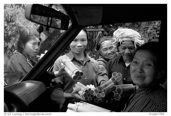 Peddlers offering sweet rice tubes for sale to traveler. Vietnam (black and white)