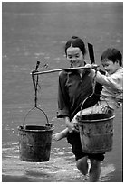 Woman of the Tay minority carrying crossing the river with child, Ba Be Lake. Vietnam ( black and white)