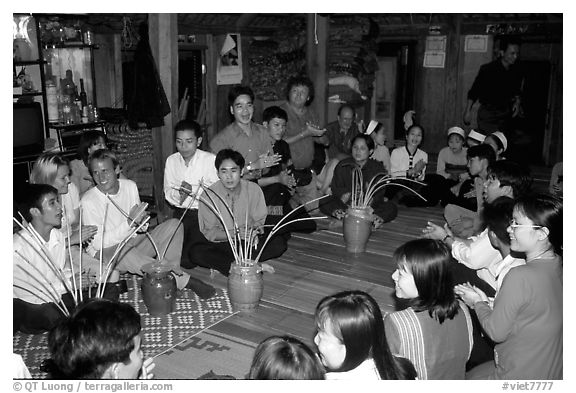 Guests in a thai house gather around jars of rau can alcohol, Ban Lac, Mai Chau. Northwest Vietnam