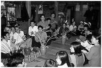 Guests in a thai house gather around jars of rau can alcohol, Ban Lac, Mai Chau. Northwest Vietnam (black and white)