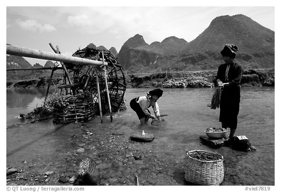 Thai women washing laundry and collecting water plants near an irrigation wheel, near Son La. Northwest Vietnam (black and white)