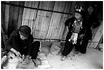 Black Dzao children look at a man  making the decorative coins used on their hats, between Tam Duong and Sapa. Northwest Vietnam ( black and white)