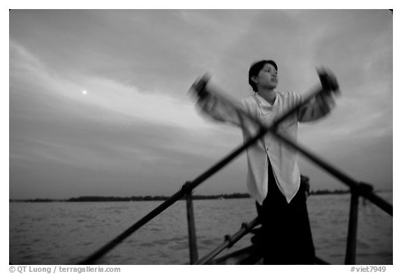 Boater using the X-shaped paddle characteristic of the Delta, sunset. Can Tho, Vietnam (black and white)