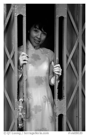 Teacher in traditional Ao Dai at her doorstep, Ho Chi Minh city. Vietnam (black and white)