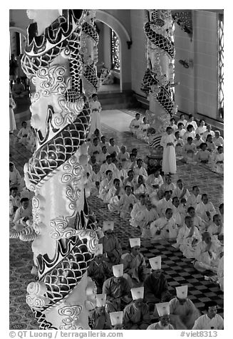 Priests and ornate columns inside the Great Caodai Temple. Tay Ninh, Vietnam (black and white)