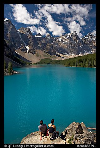 Couple sitting on the edge of Moraine Lake. Banff National Park, Canadian Rockies, Alberta, Canada