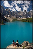 Couple sitting on the edge of Moraine Lake. Banff National Park, Canadian Rockies, Alberta, Canada ( color)