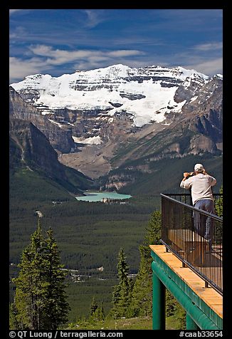 Man looking at Lake Louise through binoculars on observation platform. Banff National Park, Canadian Rockies, Alberta, Canada