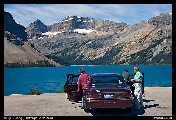 Tourists stepping out of a car next to Bow Lake. Banff National Park, Canadian Rockies, Alberta, Canada