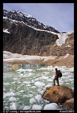 Hiker with backpack looking at iceberg-filed lake, glaciers, and mountain, Mt Edith Cavell. Jasper National Park, Canadian Rockies, Alberta, Canada (color)