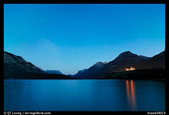 Waterton lake by night with stars in the sky in lights of Price of Wales Hotel. Waterton Lakes National Park, Alberta, Canada