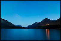 Waterton lake by night with stars in the sky in lights of Price of Wales Hotel. Waterton Lakes National Park, Alberta, Canada ( color)