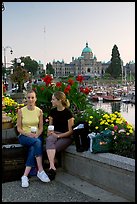 Women with shopping bags and coffee cups at the Inner Harbour, sunset. Victoria, British Columbia, Canada ( color)