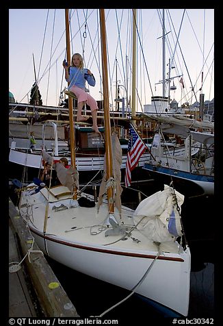 Girl swinging from the mast of a small sailboat, Inner Harbour. Victoria, British Columbia, Canada (color)