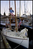 Girl swinging from the mast of a small sailboat, Inner Harbour. Victoria, British Columbia, Canada (color)