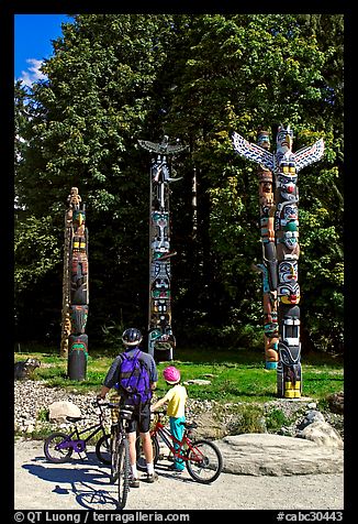 Family with bicycles looking at Totems, Stanley Park. Vancouver, British Columbia, Canada (color)