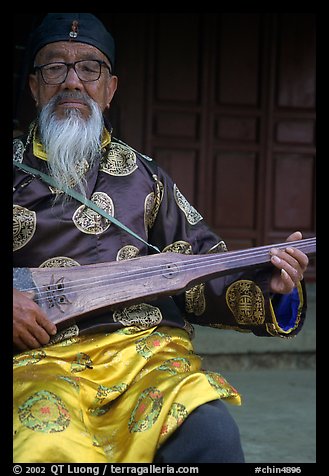 Elderly musician playing the a traditional guitar. Baisha, Yunnan, China (color)