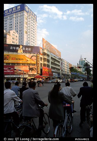 Bicyclists wait for the green light on a modern avenue. Kunming, Yunnan, China