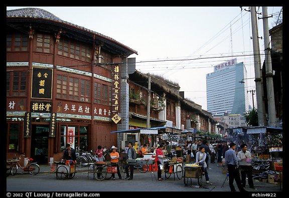Old wooden buildings, with a high rise in the background. Kunming, Yunnan, China (color)