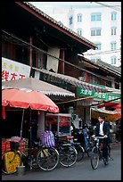 Man on bicycle in front of wooden buildings. Kunming, Yunnan, China (color)
