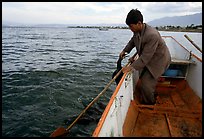 Cormorant fisherman catches one of his birds to retrieve the fish it caught. Dali, Yunnan, China (color)