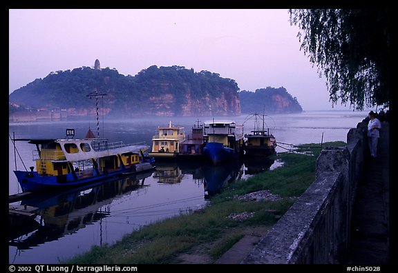 Boats along the river with cliffs in the background. Leshan, Sichuan, China