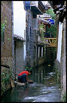Woman washes clothes in the canal. Lijiang, Yunnan, China (color)