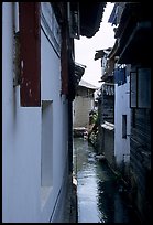 Canal sneaking narrowly between walls. Lijiang, Yunnan, China (color)