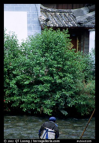 Naxi woman sitting next to a canal. Lijiang, Yunnan, China
