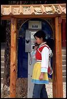Woman in Naxi dress in a telephone booth. Lijiang, Yunnan, China