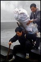 Porter getting helped to shoulder a heavy load on a back frame. Emei Shan, Sichuan, China ( color)