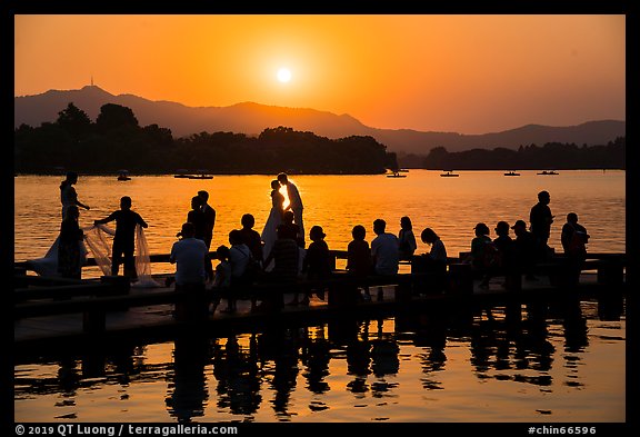 Couple embracing at sunset among crowd, West Lake. Hangzhou, China