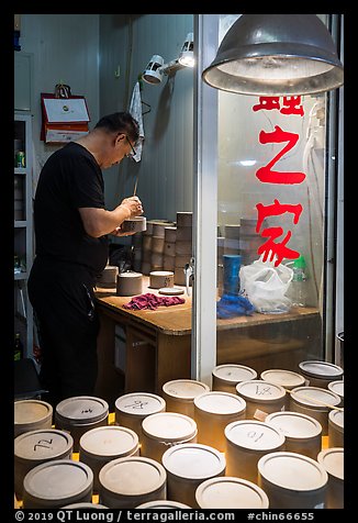Man poking fighting crickets with stick. Shanghai, China (color)