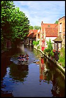 Boat on a canal lined with houses and trees. Bruges, Belgium