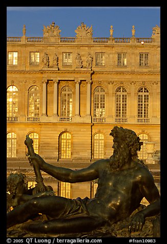 Statue, basin, and Versailles palace facade, late afternoon. France