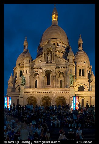 Tourists sitting on the stairs of the Sacre coeur basilic in Montmartre at night. Paris, France