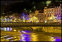 Suspension bridge at night with Christmas lights reflected in river. Grenoble, France