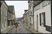 Pedestrian with umbrella in narrow street, Provins. France