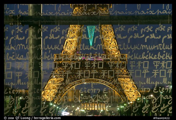 Lit Eiffel Tower seen through the words Peace written in many languages. Paris, France (color)